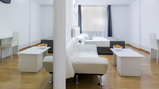 Ein modernes Hotelzimmer mit einem Bett, zwei weißen Sofas, einem Couchtisch und einem Fernseher.