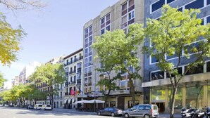 Eine moderne Stadtstraße mit mehrstöckigen Gebäuden, geparkten Autos und Bäumen.