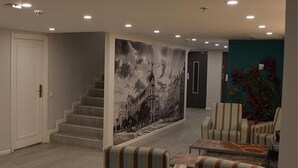 Ein modernes Interieur mit einer Treppe, gestreiften Sesseln und einer großen Stadtansicht als Wandgemälde.