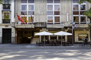 Un edificio de apartamentos con asientos exteriores y banderas.