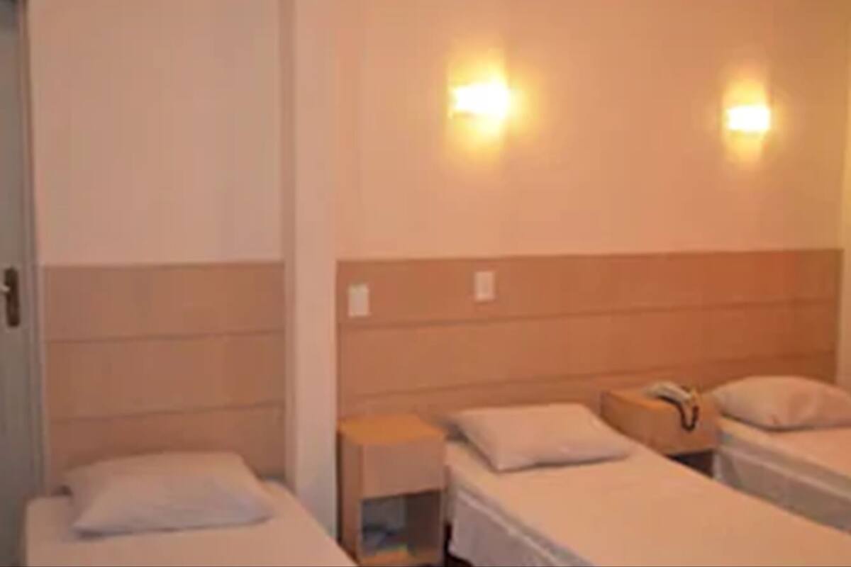 Une chambre d’hôtel avec deux lits simples, une petite table de chevet et une commode.