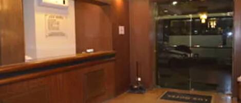 A reception area with a wooden reception desk, a glass door leading outside, and a sign on the wall.