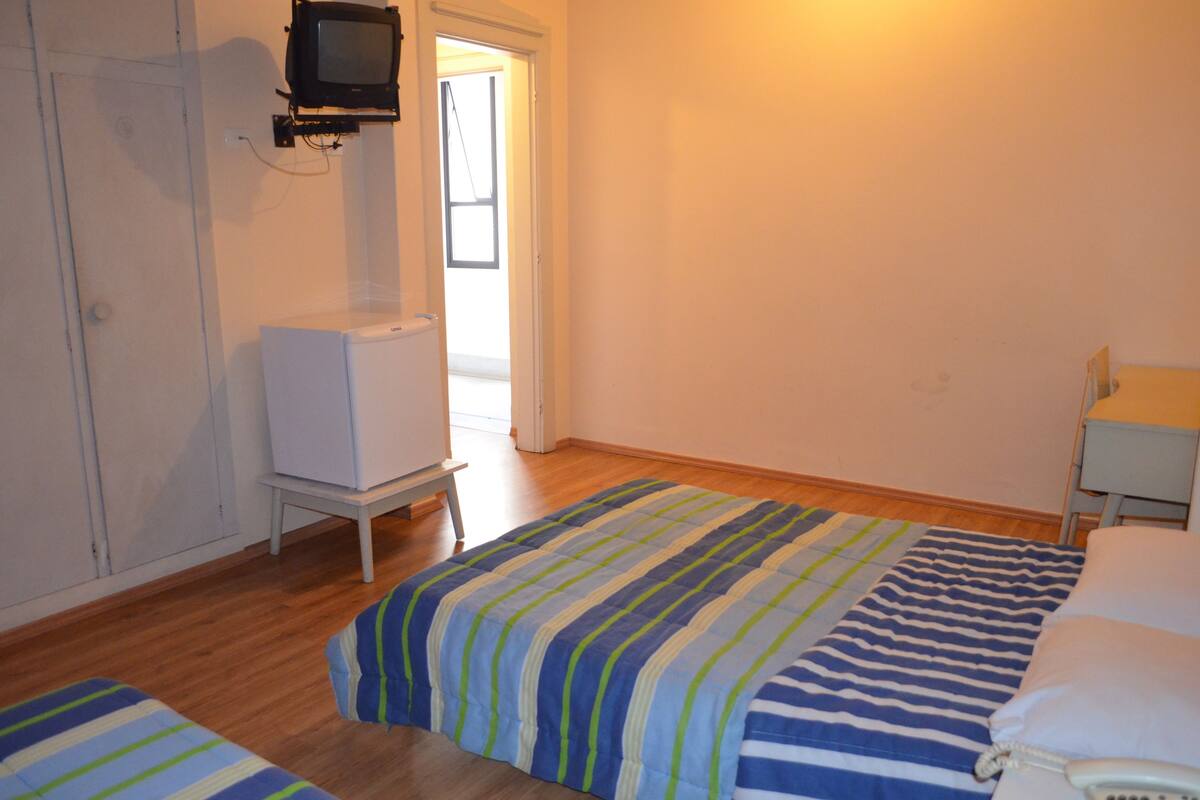 Une chambre à coucher comprenant un lit, une table de chevet, un téléviseur fixé au mur et une armoire.