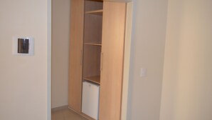 A room with a wooden wardrobe, a small white appliance, and a light switch on the wall. - Hotel Lux (São Paulo)