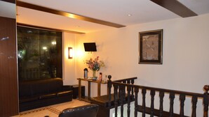 A modern living room with a sofa, a coffee table, and a staircase with a wooden railing. - Hotel Lux (São Paulo)