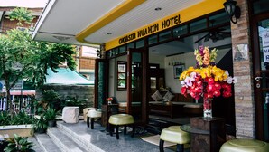 The exterior of Chom Shin Hua Hin Hotel with a yellow facade, a large floral arrangement, and outdoor seating. - Chomsin Hua Hin (Hua Hin)