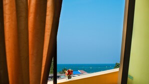 A view through a window with curtains, featuring a balcony with a vase of flowers and a clear blue sky. - Chomsin Hua Hin (Hua Hin)