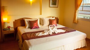 A hotel room with a neatly made bed, a bedside lamp, a framed picture on the wall, and a window with curtains. - Chomsin Hua Hin (Hua Hin)