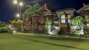 A traditional wooden building with a tiled roof, surrounded by well-maintained greenery and a paved pathway.