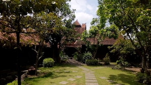 A garden with a stone pathway leading to a building with a tiled roof.