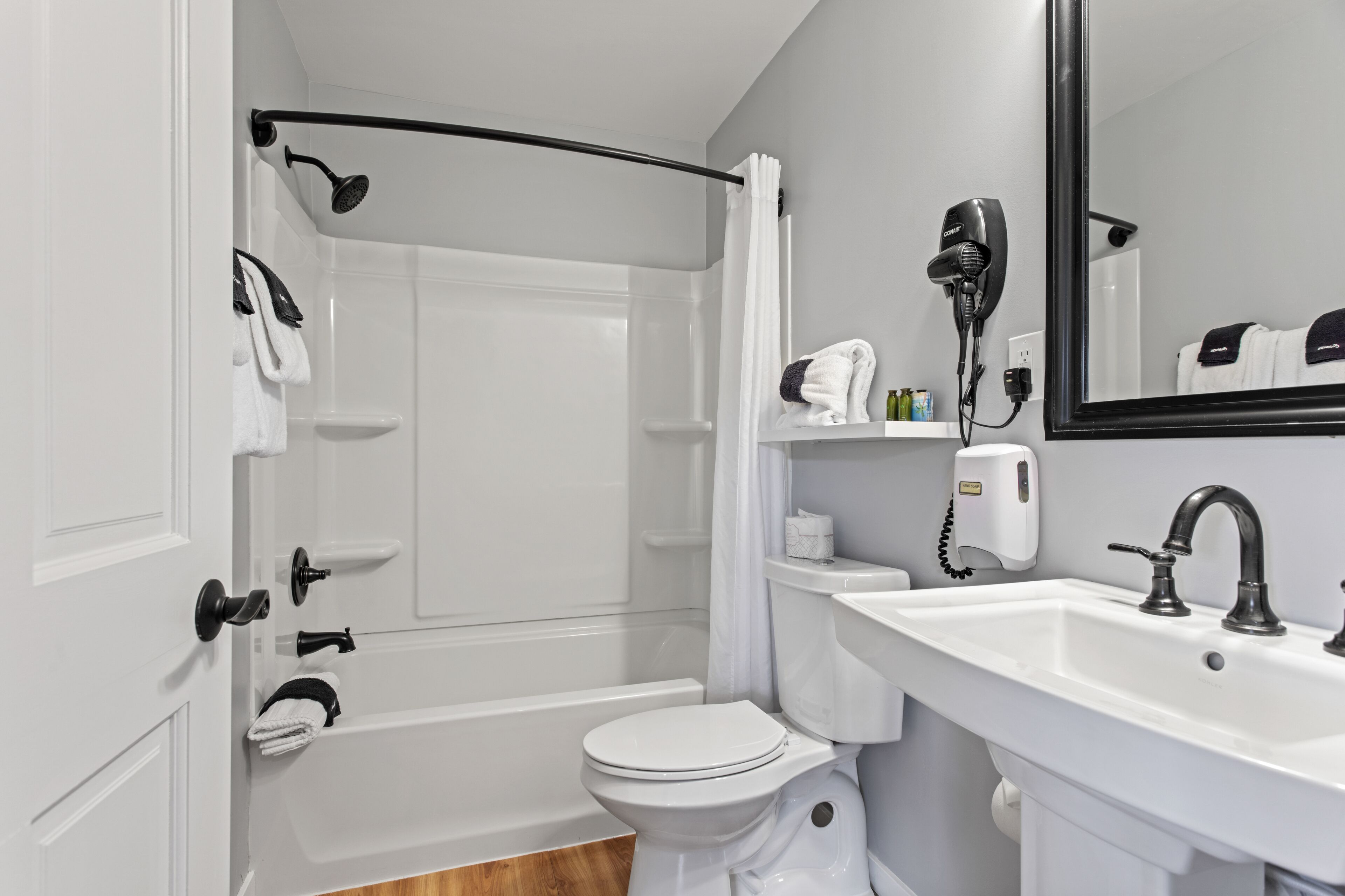 A modern bathroom with a shower, toilet, sink, and a large mirror.