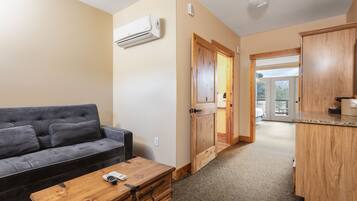 A living room with a grey sofa, a wooden coffee table, and an air conditioning unit on the wall.