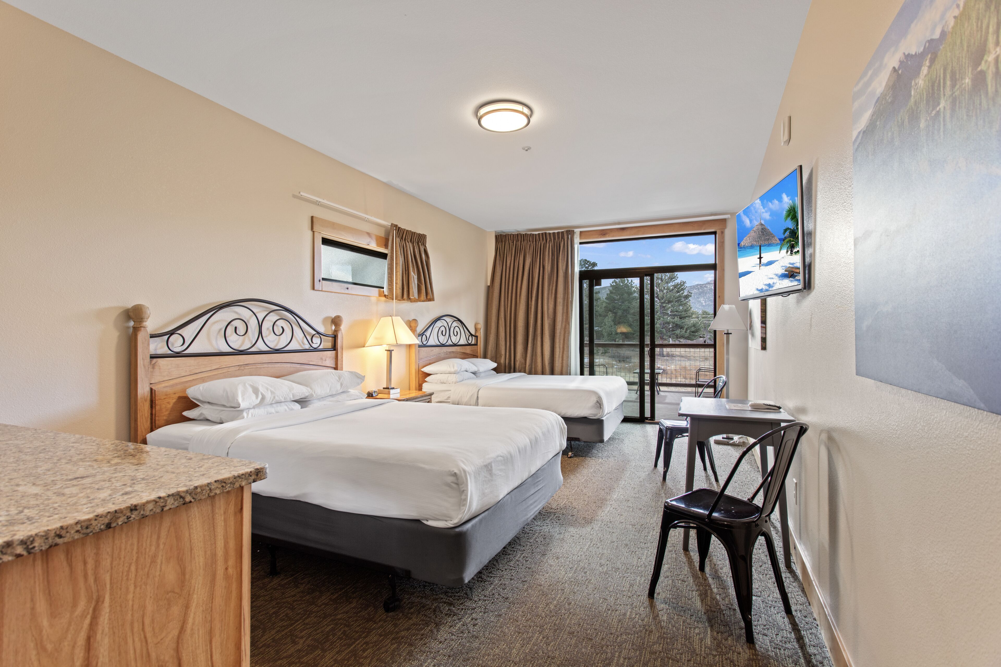 A hotel room with two beds, a desk, a chair, a TV, and a window with a view.