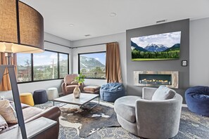 A modern living room with a large window, a fireplace, and a mountain view.