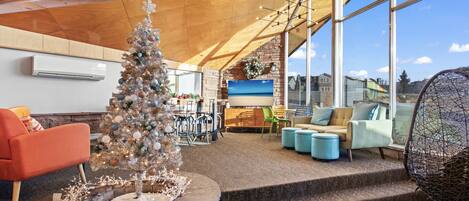 Un interior moderno con un árbol de Navidad, una zona de estar y ventanas amplias que ofrecen vistas.