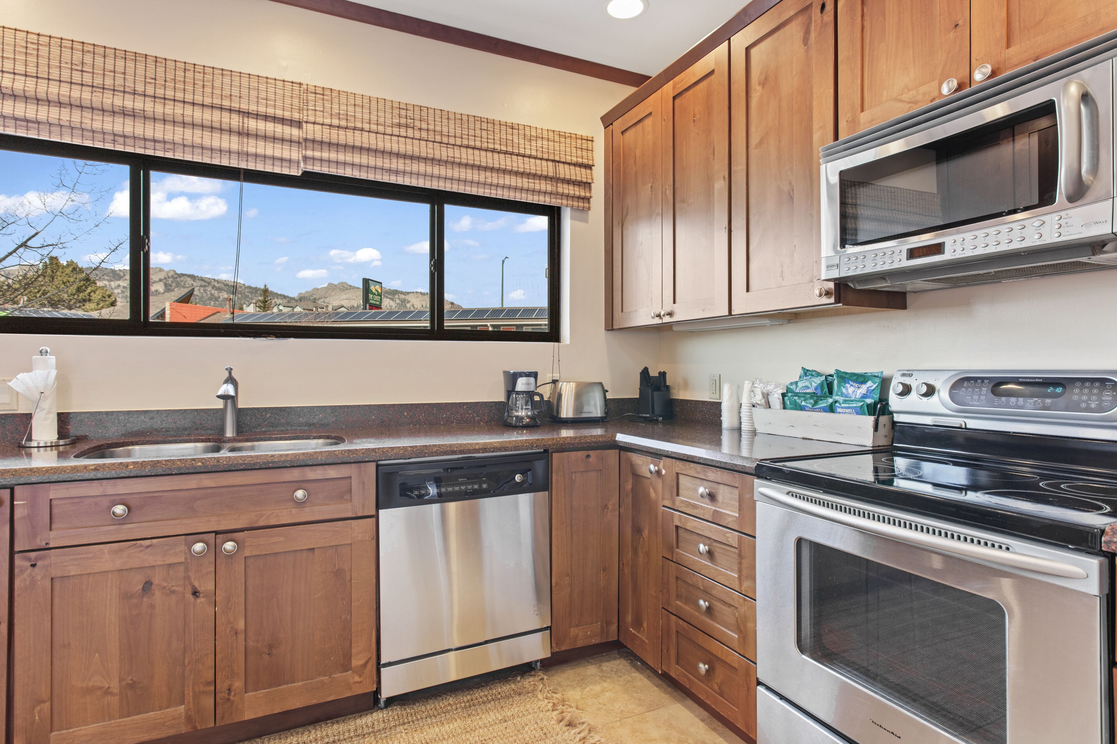 A kitchen with wooden cabinets, stainless steel appliances, a dishwasher, a microwave, and a stove.