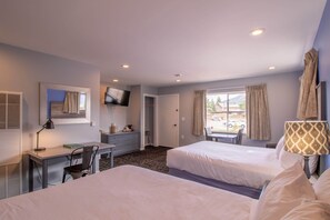 A hotel room with two beds, a desk with a chair, a TV mounted on the wall, and a window with curtains. - Coyote Mountain Lodge (Estes Park)
