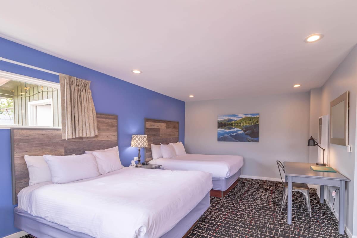 Habitación de hotel con dos camas, un escritorio y una silla.