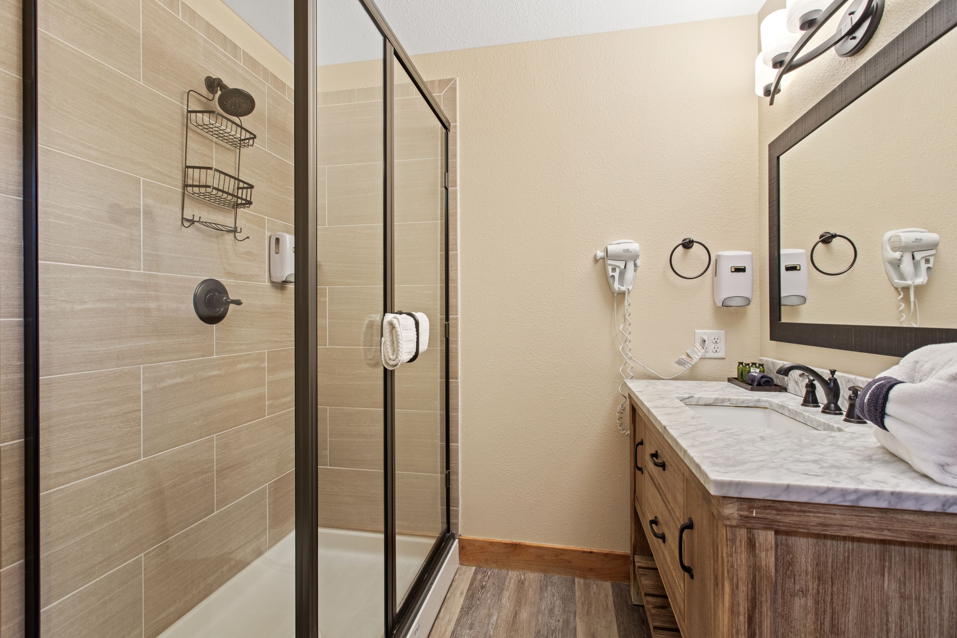 A modern bathroom with a glass shower enclosure, a marble sink, and a wooden vanity.