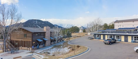 A parking lot with a building, a mountain in the background, and a clear sky.