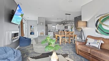 Een moderne woonkamer met een open haard, een eethoek en een keuken op de achtergrond.