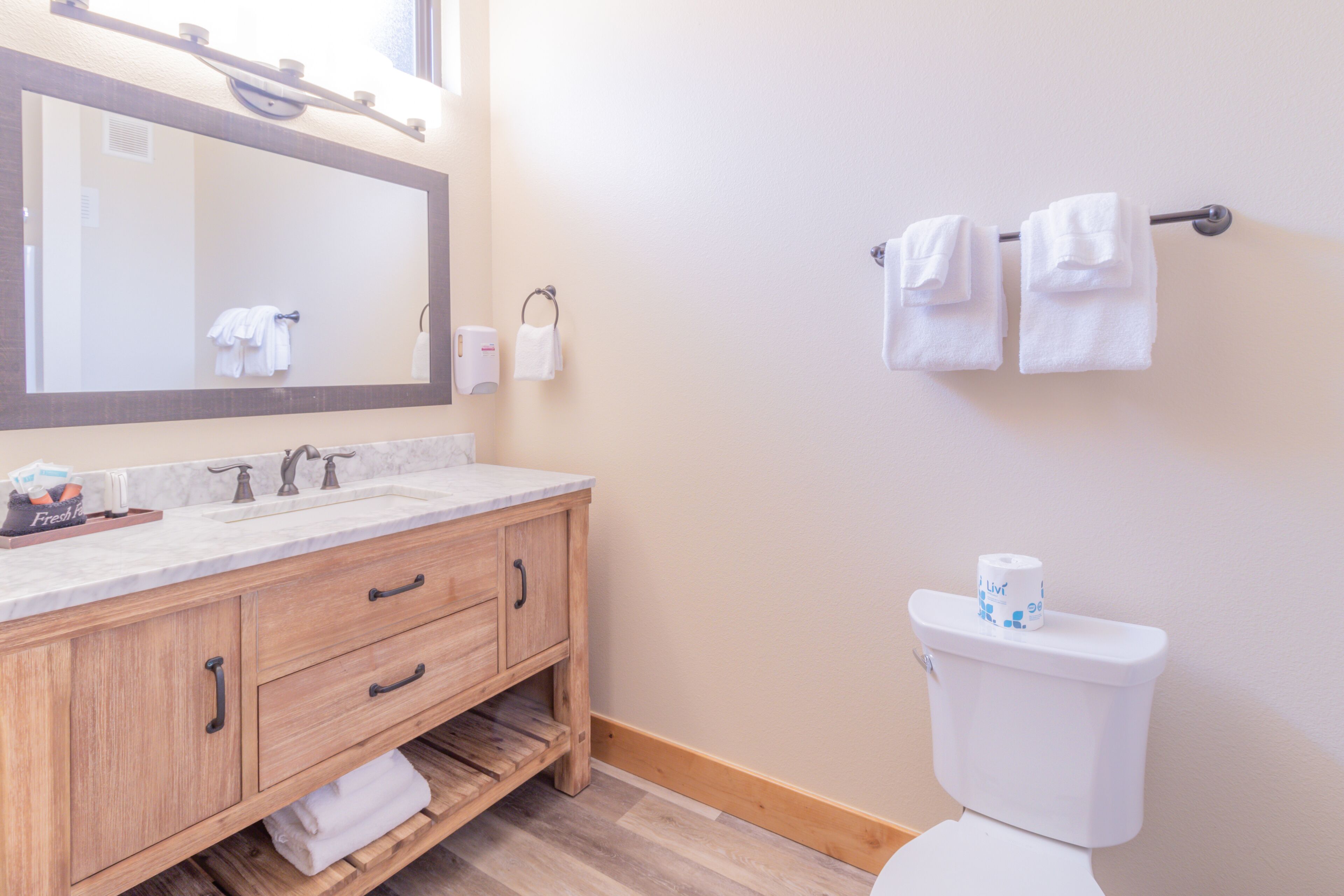 A bathroom with a wooden vanity, a sink, a mirror, and a toilet.