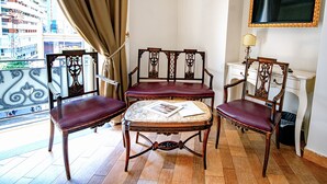 A corner room with a balcony, a table with chairs, a mirror, and a TV on the wall.