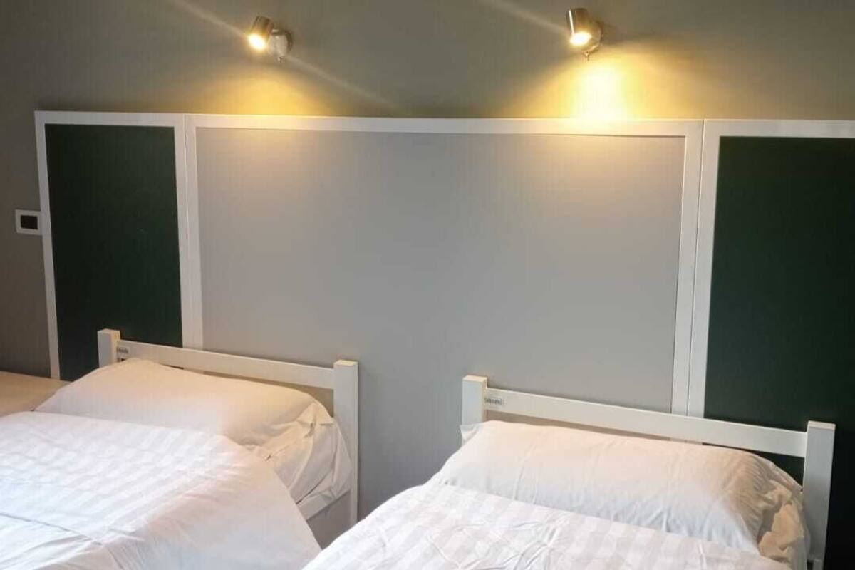 Una habitación con dos camas individuales, cada una con cabecero blanco y una mesita de noche.