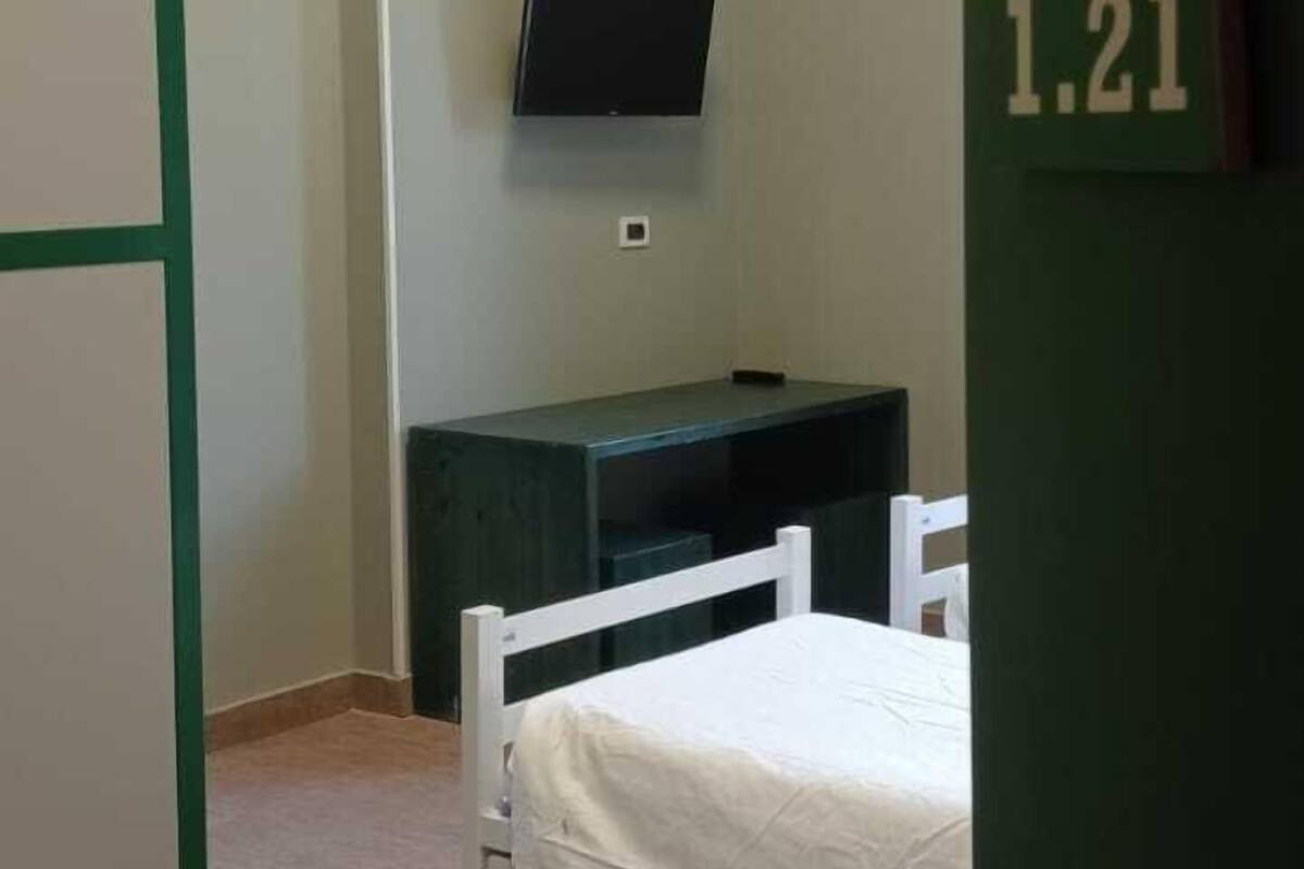 Una habitación con una cama, un escritorio, un televisor y una puerta con un número.