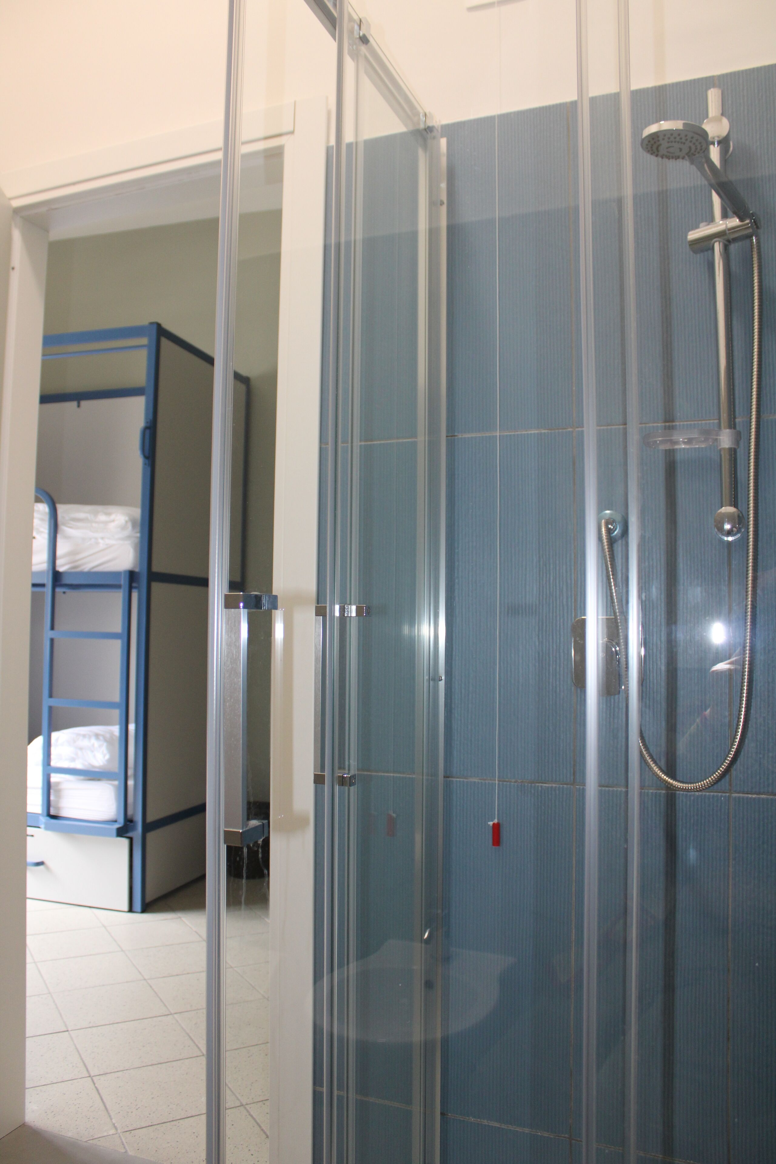 Cabina de ducha con puerta de cristal, alcachofa y toallero.