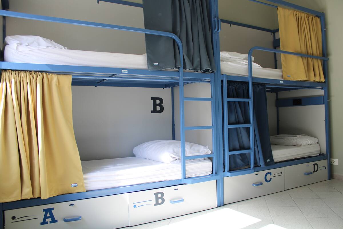 Habitación con literas, cajones identificados y cortinas.
