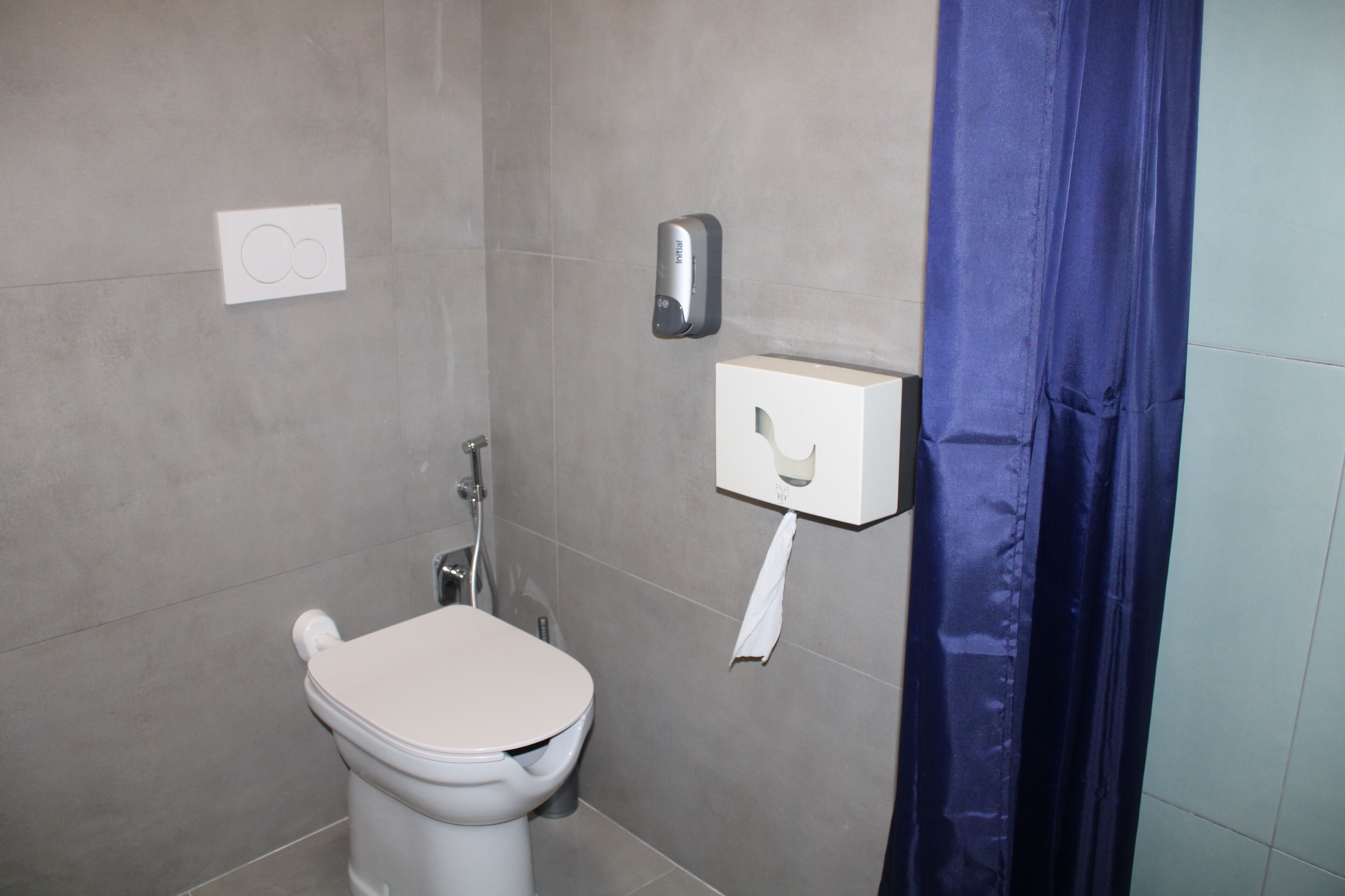 A bathroom with a toilet, a paper towel dispenser, and a hand dryer.