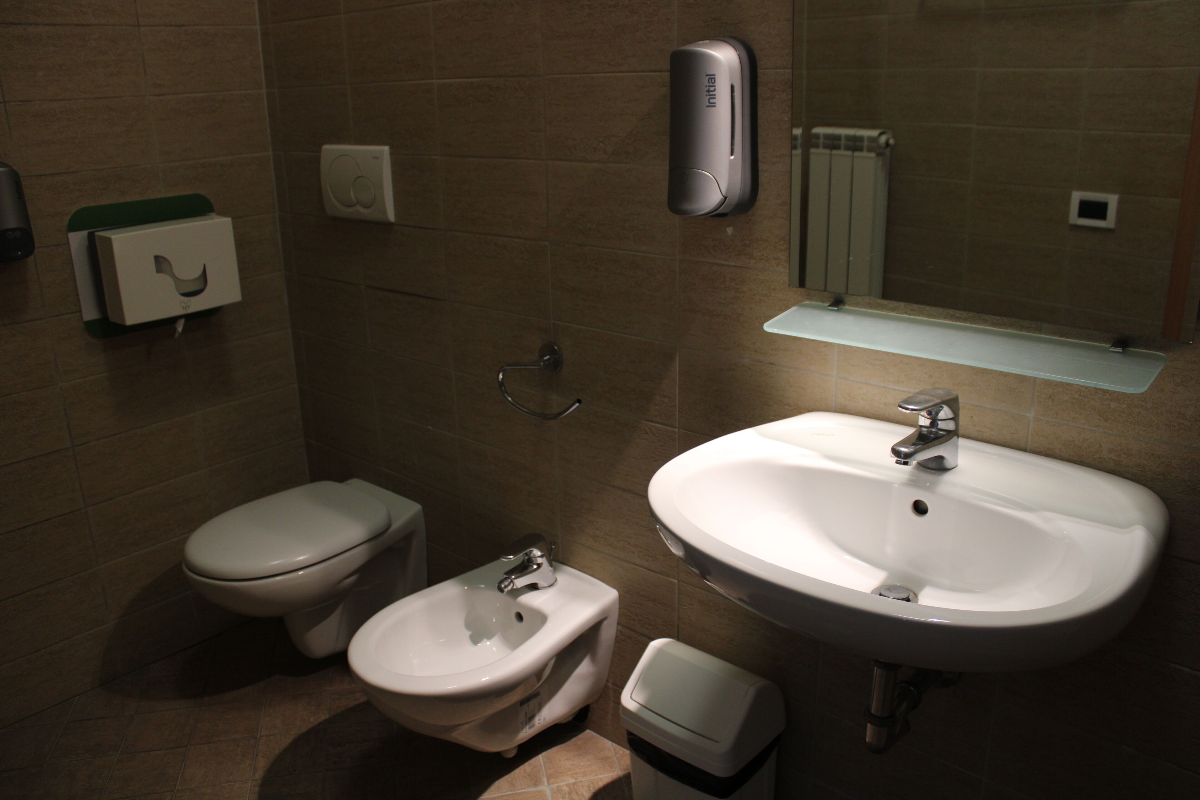Un bagno con il water, bidet, lavandino e un cestino.