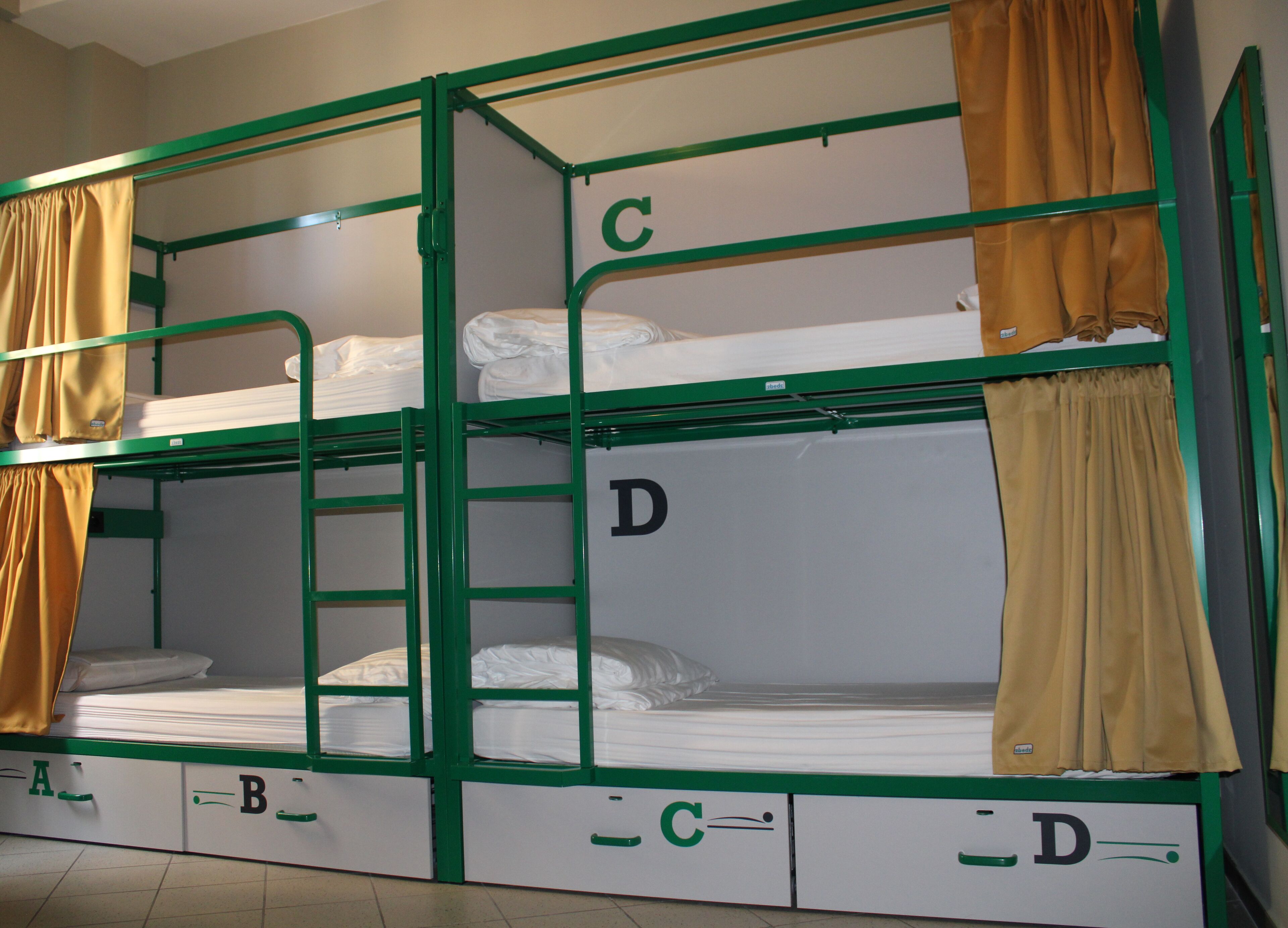 Habitación con literas en tres niveles, cada una identificada con una letra (A, B, C, D).