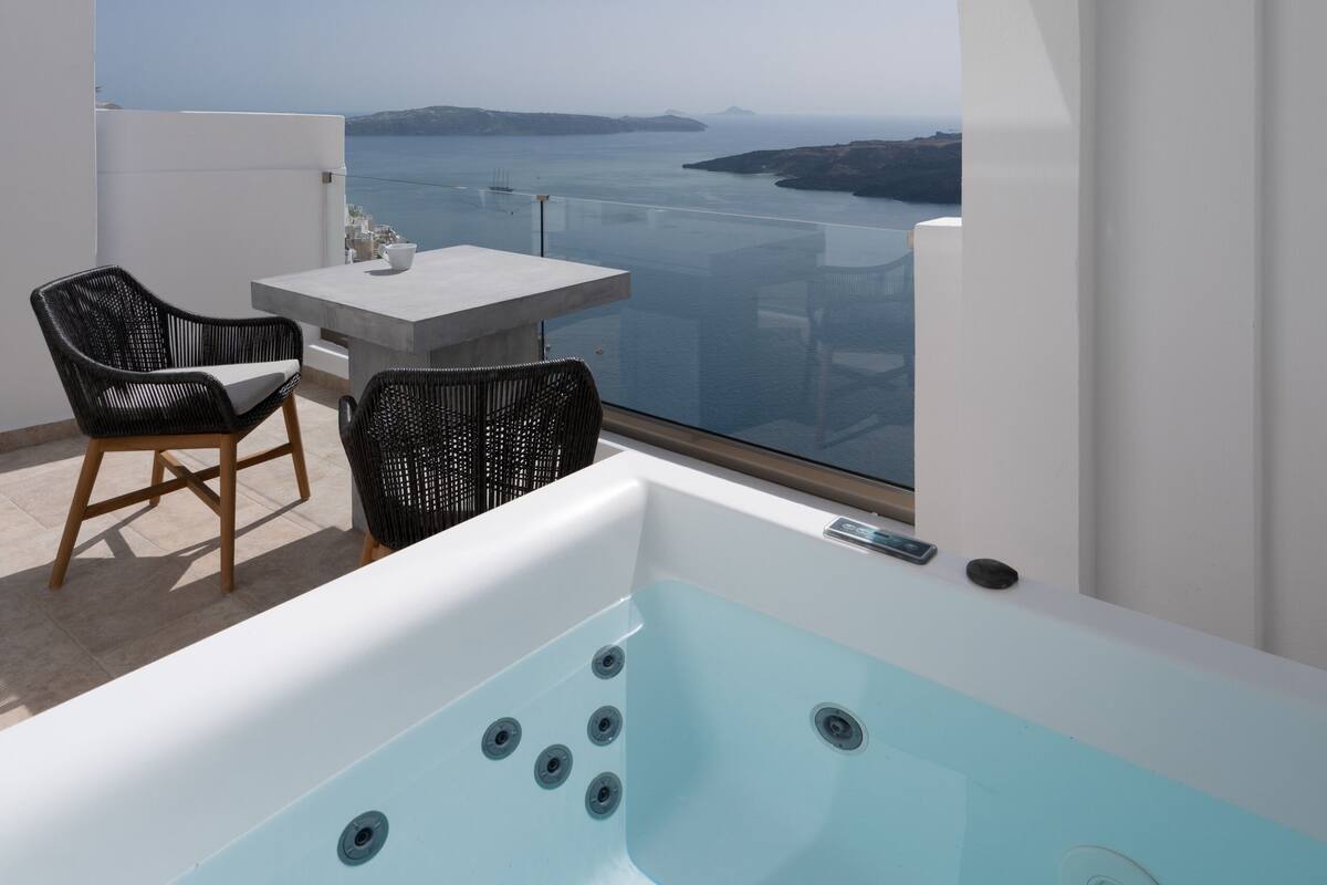 Ein moderner Balkon mit Whirlpool, zwei Korbstühlen und einem Tisch.