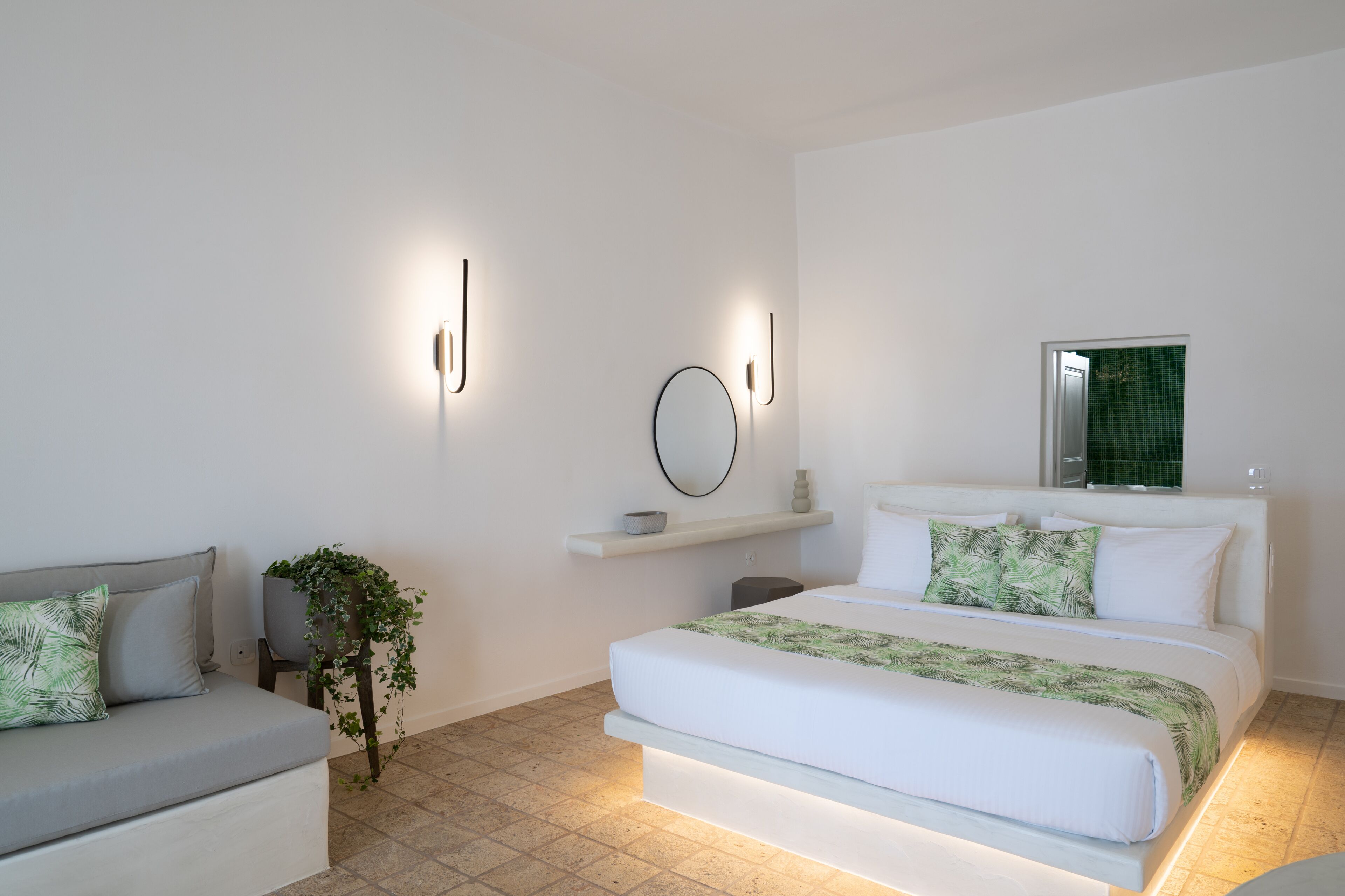 Un dormitorio moderno con cama, sofá, una mesita y estante en la pared.