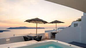Zona de piscina en la azotea con dos sombrillas, un jacuzzi y vistas al mar al atardecer.