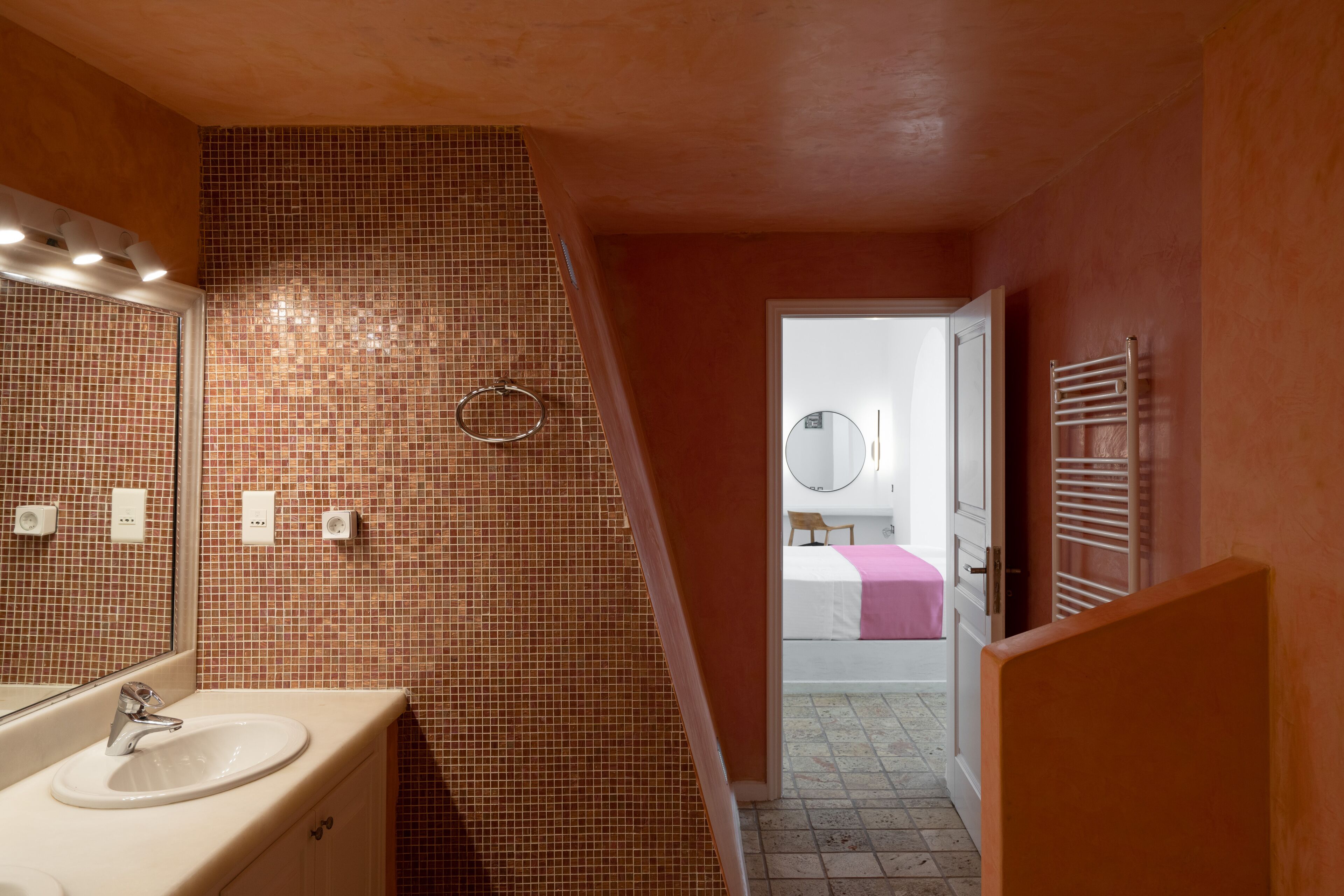 Un baño con pared de azulejos, un lavabo y un espejo.