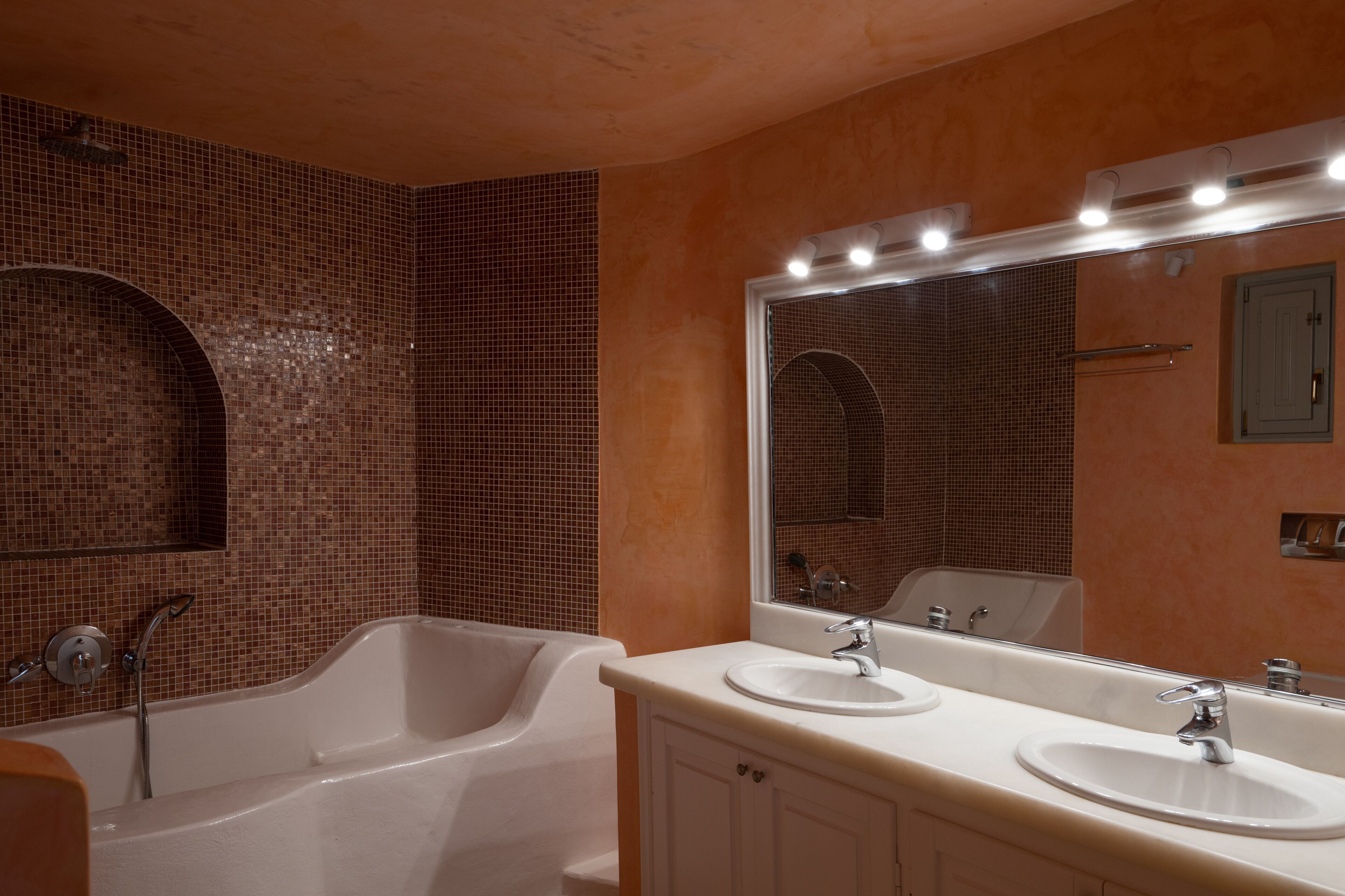 A bathroom with a bathtub, two sinks, a large mirror, and a shower area.