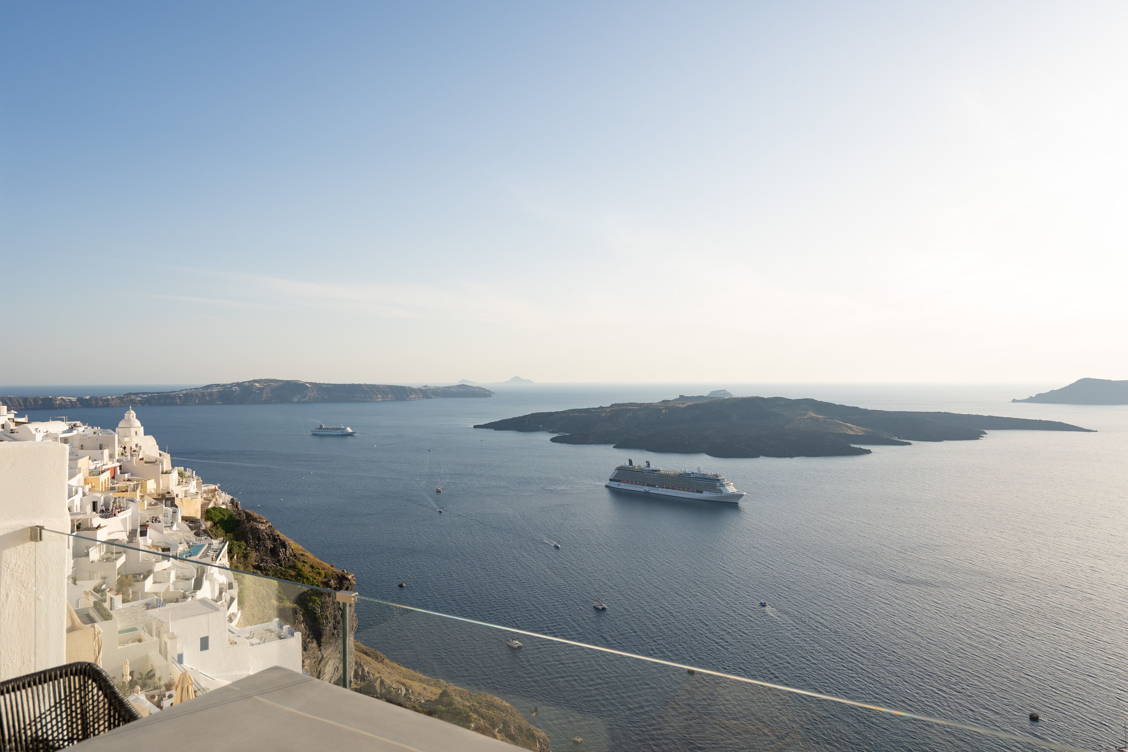 A coastal view with a cruise ship in the water, buildings along the shore, and a clear sky.