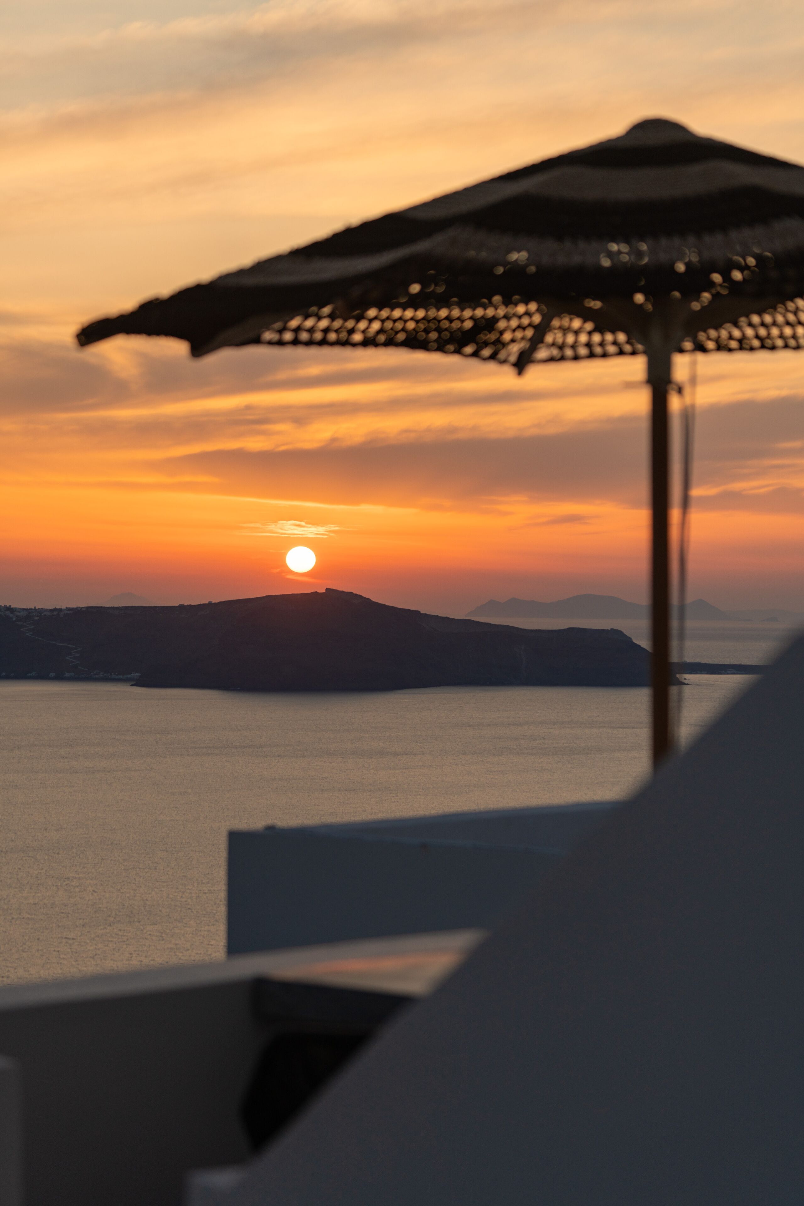 Une vue sur le coucher de soleil, avec un parasol de plage au premier plan.