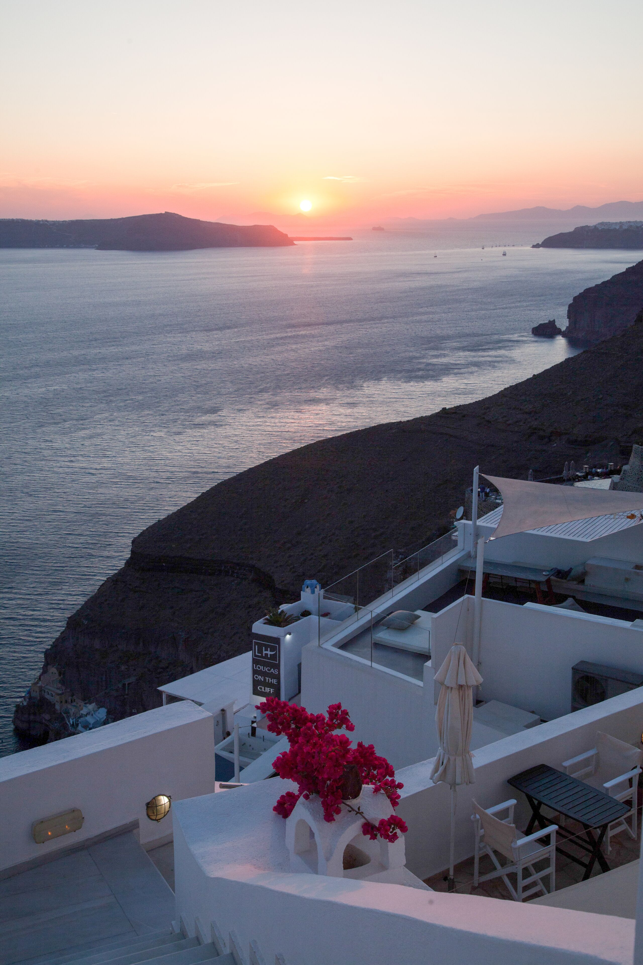Terraza de hotel junto a la costa con vistas al mar y al atardecer.