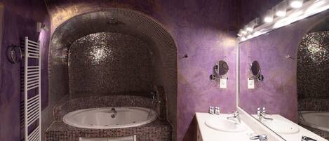 Un baño con una bañera grande, dos lavamanos y un espejo.
