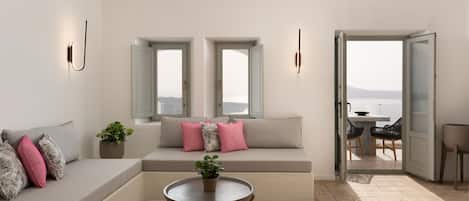 A modern living room with a sofa, a round coffee table, and a view through an open door.