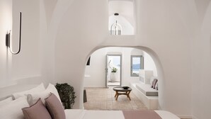 Un dormitorio moderno con una cama grande, una mesita redonda y vistas a un balcón con asientos a través de un arco.