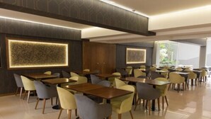 A modern dining area with multiple tables and chairs, featuring a geometric wall pattern and recessed lighting. - Urbana Class Hotel (Mendoza)