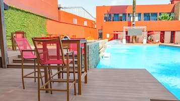 Una piscina al aire libre, sombrillas, sillones reclinables de piscina