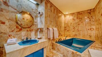 Un baño con paredes de mármol, un espejo grande, un lavabo, una bañera y un perchero para toallas.