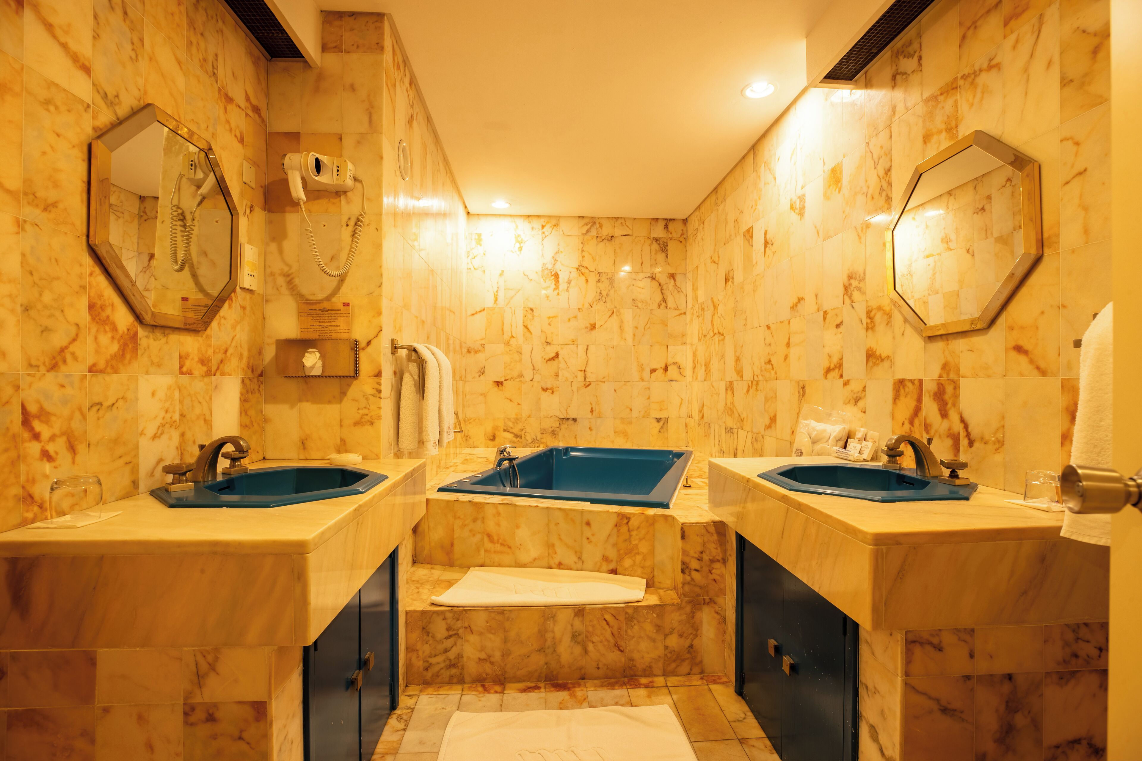 Un baño con dos lavamanos, una bañera y un espejo.