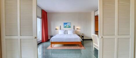 A bedroom with a bed, a nightstand, a lamp, and a painting on the wall.